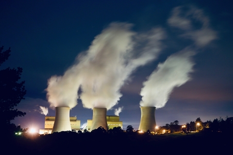 Three power station stacks spew forth smoke at night