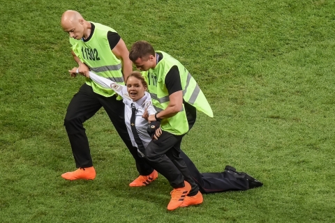 a female protester is dragged from a soccer field by security personnel
