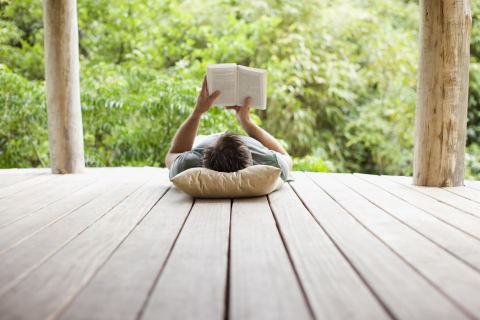 a person lies down on a patio reading a book