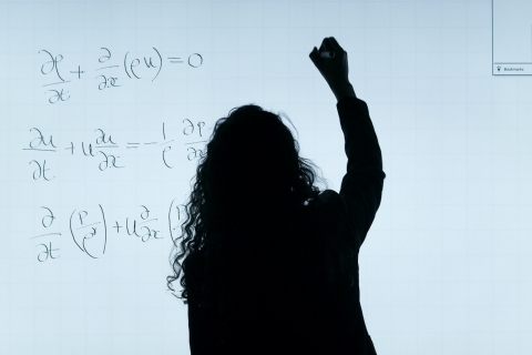 a woman writes formulas on a whiteboard