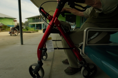 A person sitting while holding a walking frame