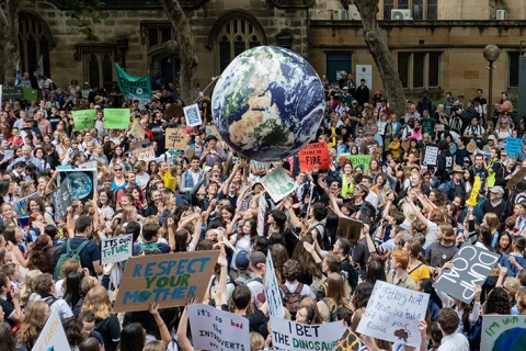 Climate change protest marchers toss around a large inflatable globe