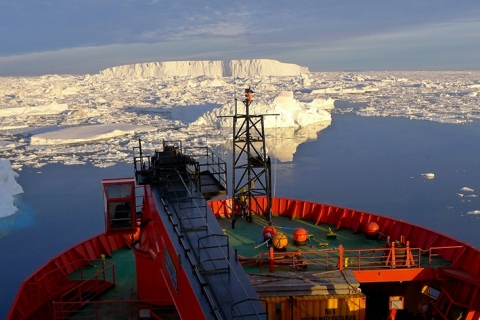Icebergs and ice sheets can be seen ahead of the bow of an ice-breaker vessel