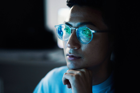 Green code reflected in programmers glasses