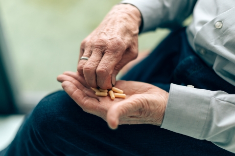 an elderly person handles pills and medication