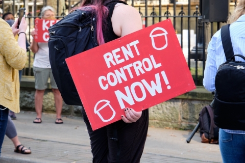 protester holding a rent control now sign at a housing crisis rally