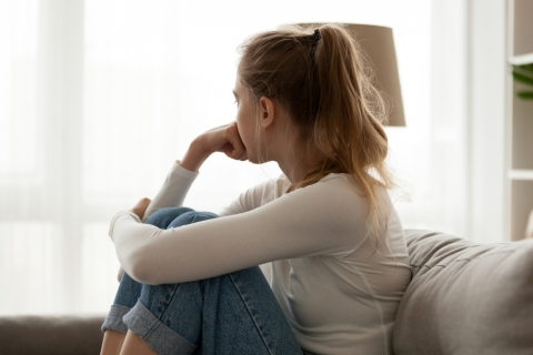 Young worried woman looking out the window