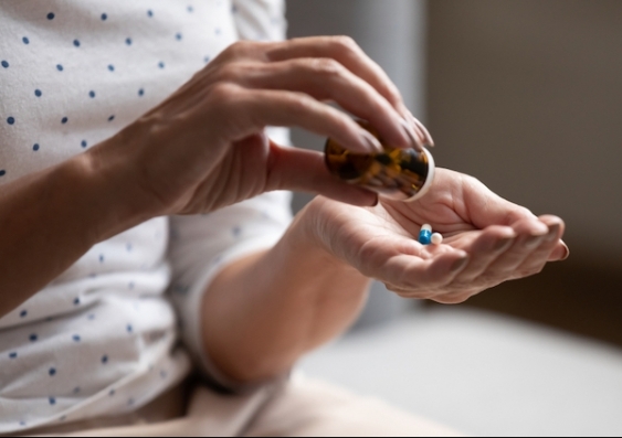 A woman pours capsules of medication into her hand