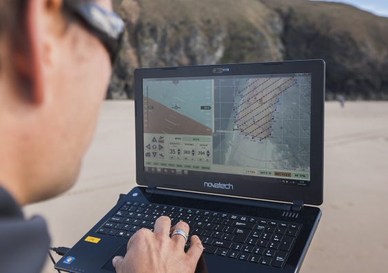 A person uses a laptop on a beach to analyse weather patterns