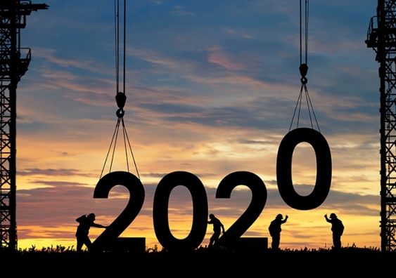 Silhouette of construction workers lowering giant numbers of 2020 into place