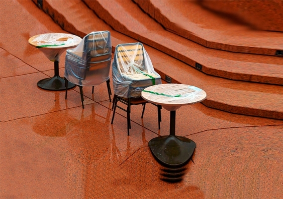 Tables and chairs stacked and wrapped in plastic outdoors
