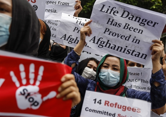 People waving signs protesting government inaction in granting amnesty to Afghani refugees