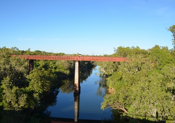 A train line is reflected in the water of the Daly River, Northern Territory