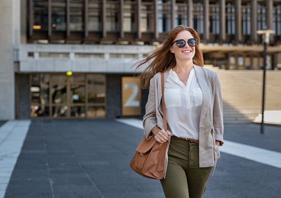 A woman with sunglasses on smiles as she leaves for the day