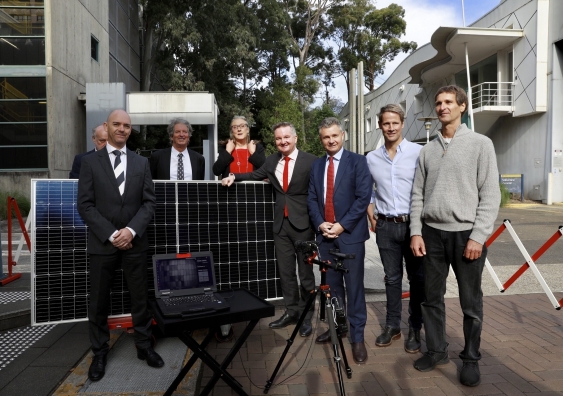Professor Renate Egan and Professor Martin Green standing with Minister Chris Bowen and researchers from UNSW with solar panel in background. 
