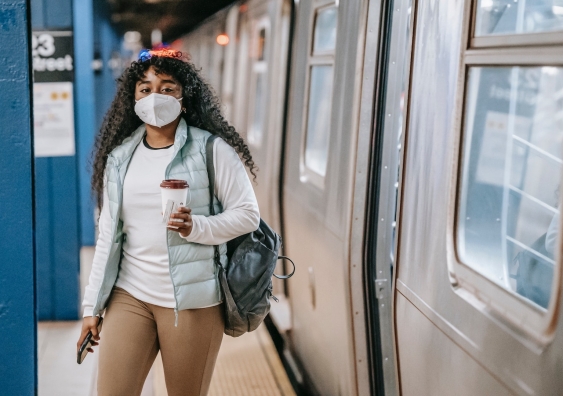 a woman leaves a commuter train wearing a face mask