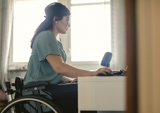 a woman works at her computer while sitting in a wheelchair