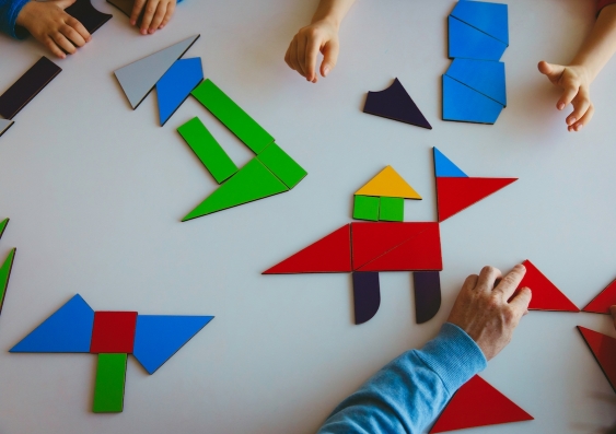 aerial view of people playing with colourful tangram puzzles on a table