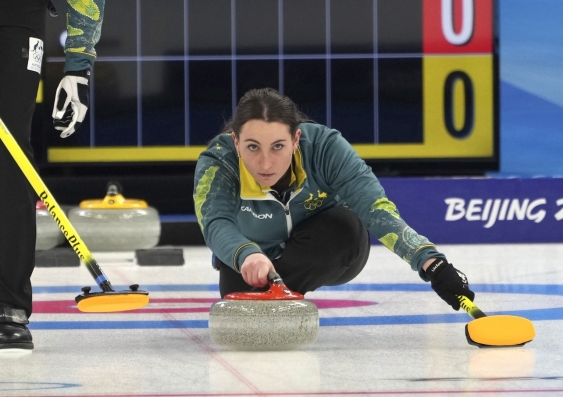 an olympian curler crouches low to the ice while competing