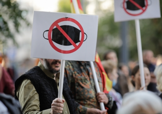 An anti-mask protest, with picket signs showing a cross through a face mask