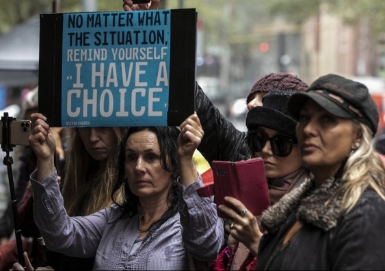 Group of women at an anti-vaccination protest, one holding a sign that says "No matter what the situation, remind yourself 'I have a choice'."