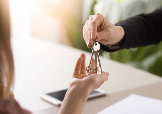 Close up of young woman taking keys from real estate agent after signing rental lease contract