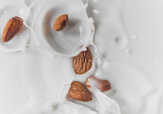 close up shot of some almonds dropped in almond milk from above