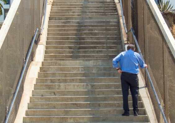 An elderly person walking up a flight of stairs