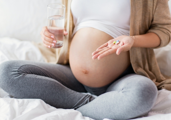 A pregnant person holding pills