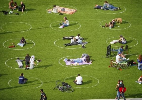 People sitting in social distancing circles marked on grass