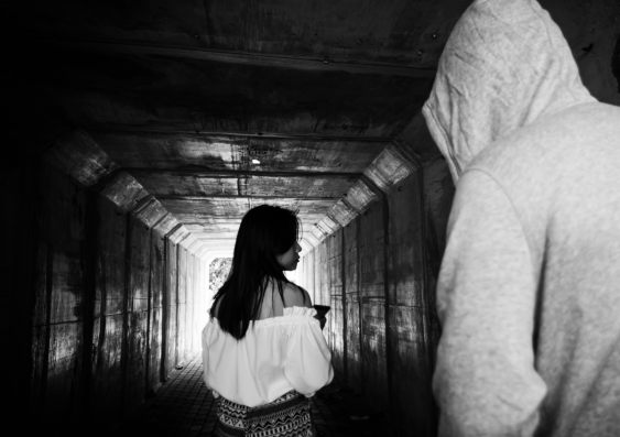 Man in hoodie approaching a women walking in tunnel