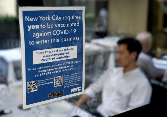 sign on restaurant window stipulating people have to show proof of vaccination