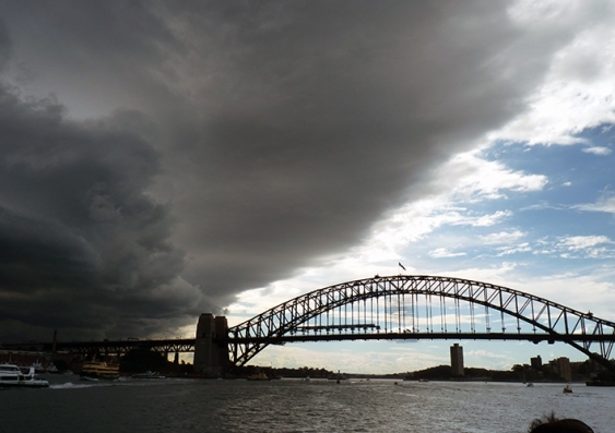 Very ominous and dark rain clouds move in over the Sydney Harbour Bridge on an otherwise sunny day