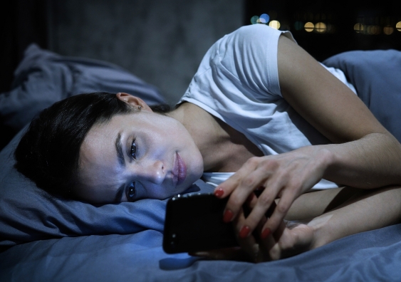 woman in bed looking at smartphone