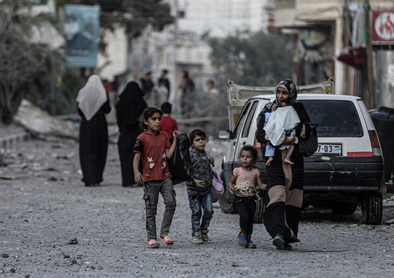 A Palestinian family walks through a bombed street in Gaza