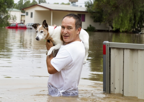 A man leaving his home walking through flood waters.