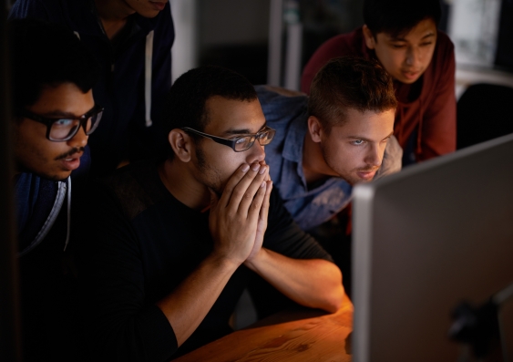 Shot of a group of young designers staring tensely at a monitor