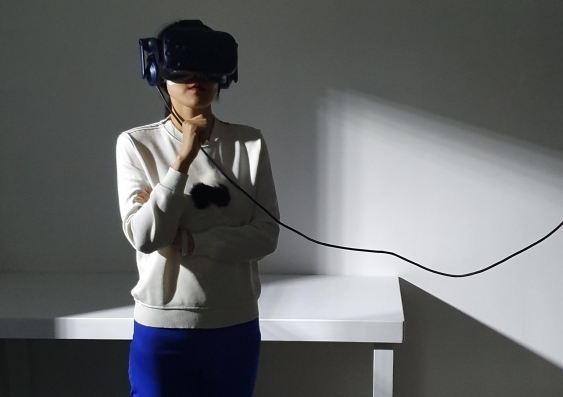 Woman using VR goggles to experience The Edge of the Present VR experience photo - Jessica Maurer