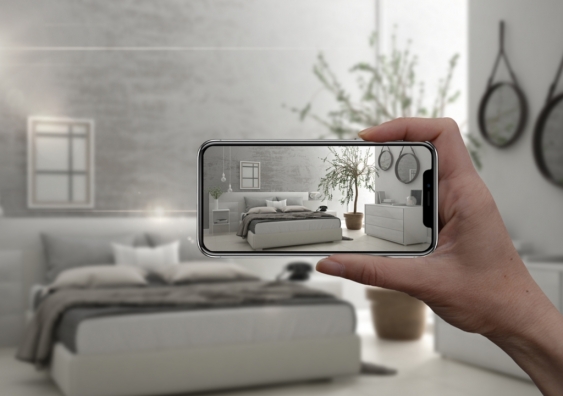 Hand holding smart phone with AR application simulating a bedroom