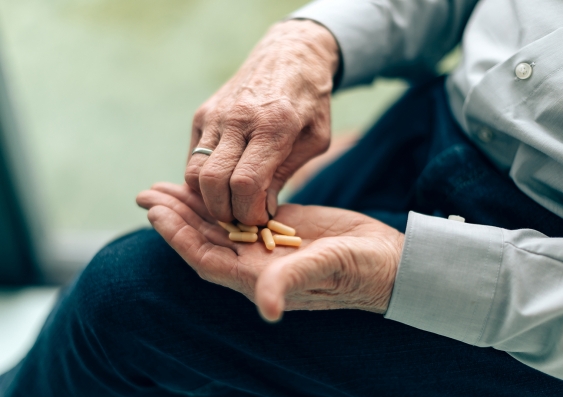 an elderly person handles pills and medication