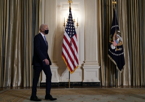 joe biden walks past american flags to a press briefing