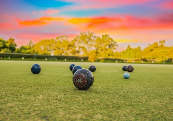 lawn bowls balls in a field after the game with a colourful sunset