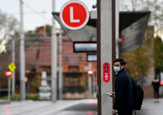 masked man waits for the light rail in sydney