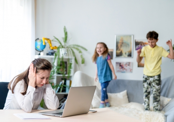 Mother trying to work on laptop at home with two kids