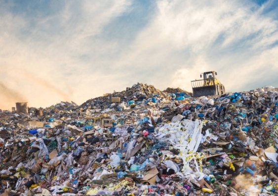 Truck drives over mountain of waste in landfill