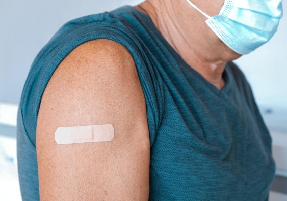 Older person's arm with a bandaid after being vaccinated