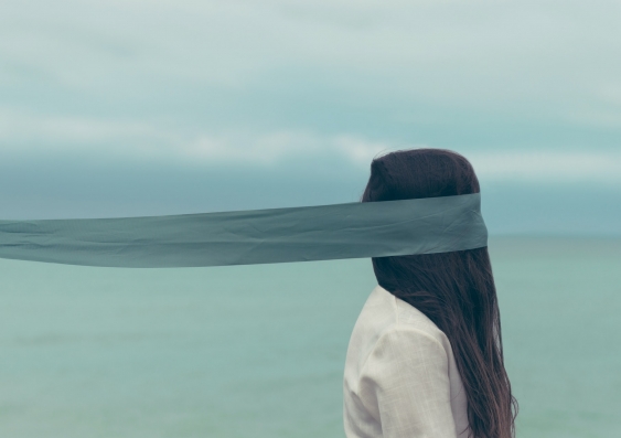 Blindfolded woman with long hair by the seaside
