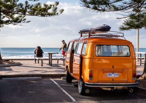 parked orange van overlooking beach