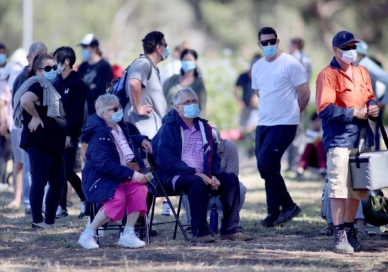 people wearing facemasks queueing for coronavirus tests