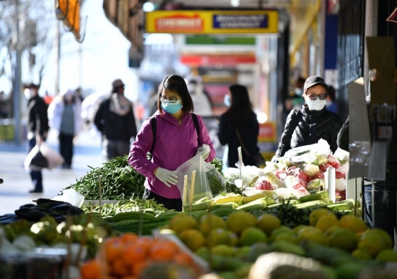 People wearing masks shopping at an outdoor fruit market